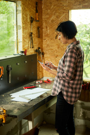 Female business owner using digital tablet in workshop, industrial woman engineer working with...