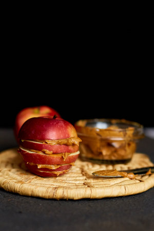 Red slices sandwich or burger of apple with peanut butter on dark background, healthy snack, nutrition and diet food.の写真素材