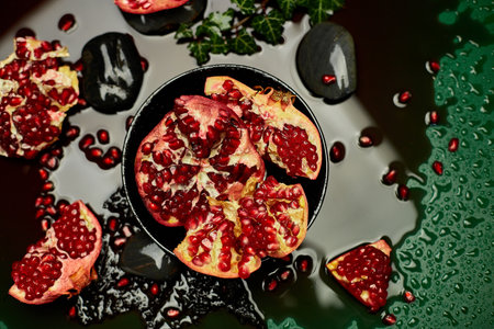 Flat lay Piece of  pomegranate and whole fruits on black and green background with juice drops, space for text, healthy drink conceptの写真素材