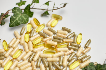 Pills, medical tablets with green plants, leaves on white background, Natural herbal medicine concept, Vitamins and omega oils for vegansの写真素材