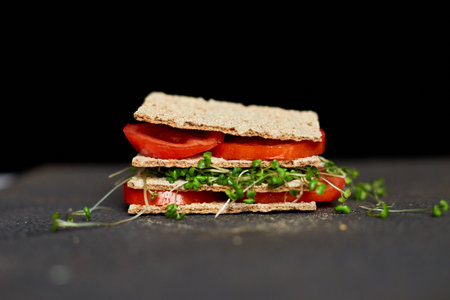 Healthy vegan sandwich with crisp rye bread tomatoe and microgreens on dark background, Diet nutritional food.の写真素材
