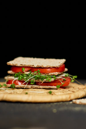Healthy vegan sandwich with crisp rye bread tomatoe and microgreens on dark background, Diet nutritional food.の写真素材