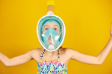 Happy child teenager girl with in swimsuit and snorkeling mask in studio on yellow background, summer vacation Funny face, wow emotionsmood,の写真素材