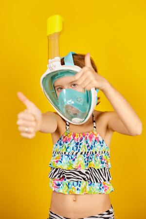 Happy child teenager girl with in swimsuit and snorkeling mask in studio on yellow background, summer vacation Funny face, wow emotionsmood,の写真素材