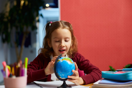 Happy schoolgirl at workplace studying globe in classroom, Back to school, education concept.
