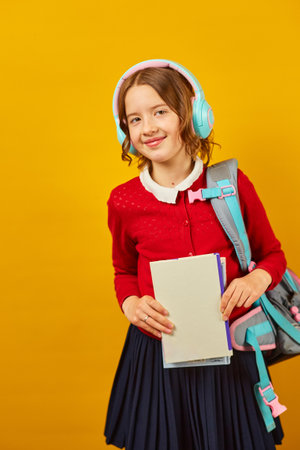 Schoolgirl with backpack, headphone and books in hand back to schoolの写真素材