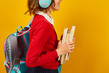 Unrecognizable Schoolgirl with backpack, headphone and books in hand back to schoolの写真素材