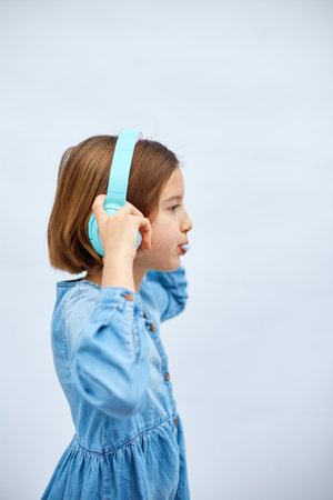 Girl teenagerwith chewing gum listening to music in headphones on white background, wireless earphones enjoying music dancing , Modern technology, Protect Developing Earsの写真素材