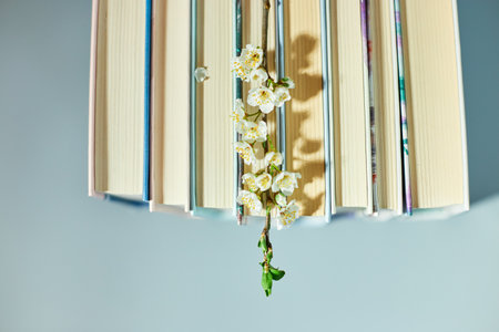 Stack of books with branch flowers, World book day, knowledge and creativity concept, spring, summer mood, copy space, top view.の写真素材
