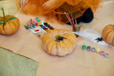 Unrecognizable Close Up of the hand of a young girl decorating an orange pumpkin, drawing face Jack-O-Lantern for Halloween with a paint at home. Holiday decoration conceptの写真素材