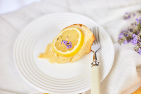 Piece of lemon cake on white table with lavender flower bouquet