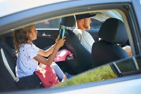 Joyful man driving car with daughter, going on trip during summer vacation, family vacation buying and renting a car.の写真素材