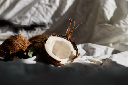 Fresh coconuts on a white cloth with one halved coconut revealing its inner flesh
