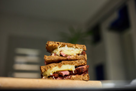 Two layers of a Reuben sandwich filled with corned beef, Swiss cheese, and sauerkraut, placed on a wooden board, highlighting a tasty meal perfect for lunchtime.の写真素材