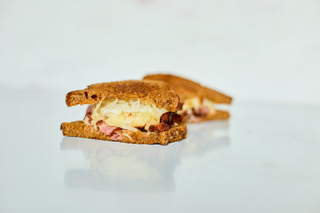 A Reuben sandwich showcases layers of corned beef, sauerkraut, and melted cheese nestled between two...