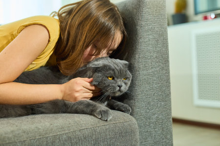Teen girl snuggles with cat at home during cozy afternoonの写真素材