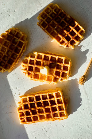 Delicious waffles topped with a touch of honey on a bright background in the morning lightの写真素材