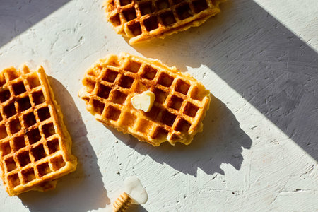 Delicious waffles topped with a touch of honey on a bright background in the morning lightの写真素材