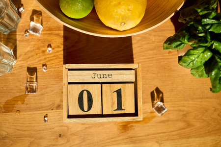 A wooden bowl filled with colorful citrus fruits sits alongside two glasses with ice and fresh mint leaves, marking the start of summer with a warm invitation to refreshment.の写真素材
