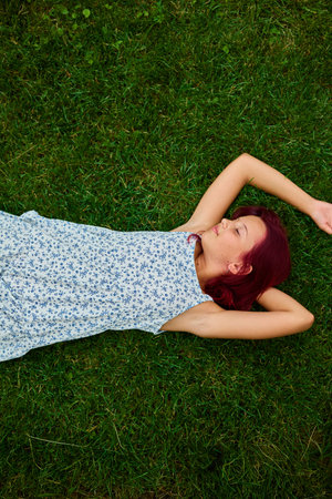 Teen girl relaxes on green grass in a peaceful outdoor setting during a sunny day