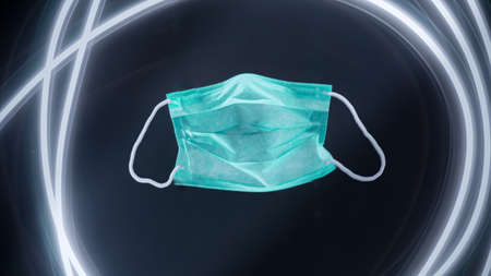 light green medical mask with eraseres on black background with shadow and light lines in 3d for virusesの写真素材