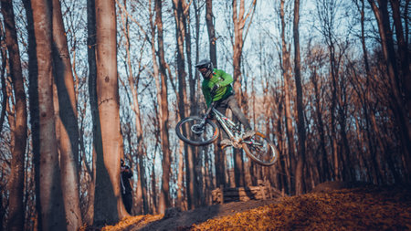 Riding on mtb bikes, downhill bikes in autumn forest on bike trails wish tricks and huge gaps and jumpsのeditorial素材