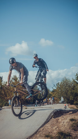 Summer riding on mtb bikes on pumptrack 4cross with tricks and big air jumps in outdoor bike parkのeditorial素材