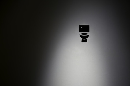 Toilet symbol in highlight concrete wall.