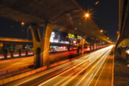 Abstract blur of night road under the expressway with thumb up.の写真素材