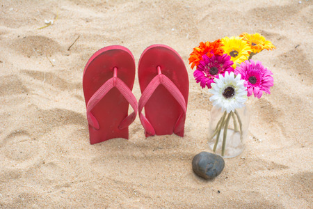 Red old slippers and flower on the sandの写真素材
