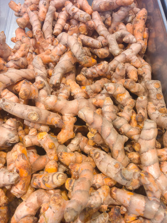 Heaps of freshly harvested turmeric roots in supermarketの写真素材