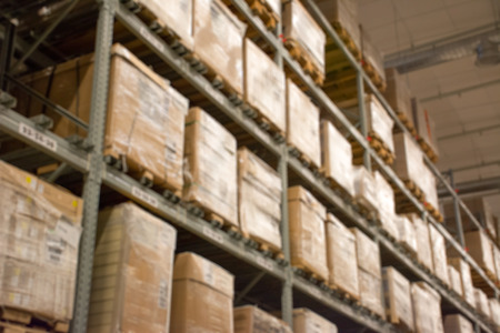 Abstract blurred boxes on rows of shelves in big modern warehouse background