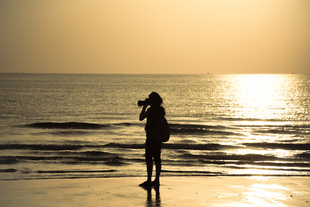 Silhouette Female photographer at sunset on the beach, chao lao beach chanthaburiの写真素材