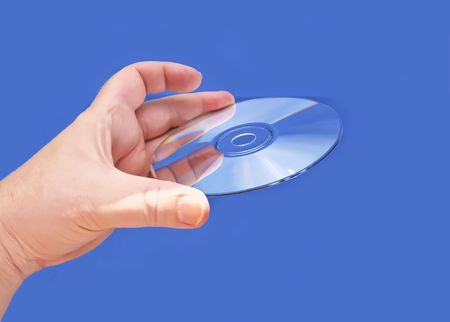 A hand holding a CD or DVD media against a blue backgroundの写真素材