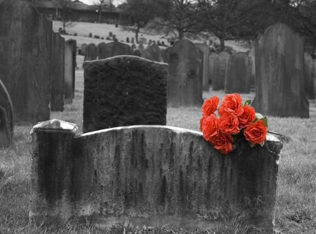 Blank headstone in graveyard with bunch of red rosesの写真素材