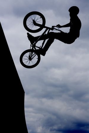 Silhouetted biker boy doing stuntsの写真素材