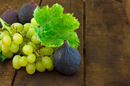 Figs and grapes on old wooden tableの写真素材