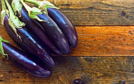 Fresh organic aubergines on rustic wooden tableの写真素材