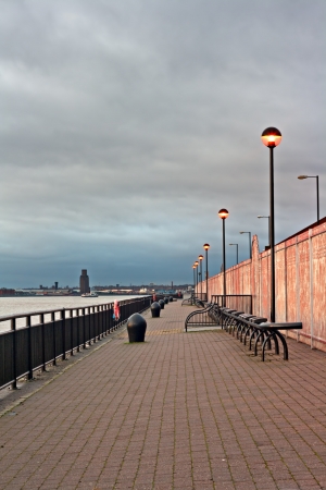 Promenade on the River Mersey, Liverpool, UK, with ferry crossing the river at sunset の写真素材