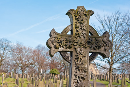 A cross in an ancient graveyard with tombstones in the backgroundの写真素材