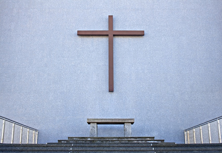 Cross with bench on exterior wall  of Cathedralの写真素材