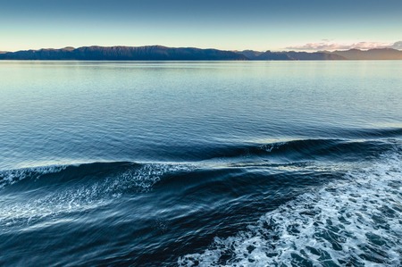 Ship bow wave ripple Port side and dawn lit mountains in background. Alaska, USAの写真素材