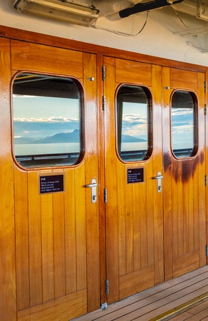 Cruise ship heavy varnished wood exterior doors with windows reflecting the sea.の写真素材