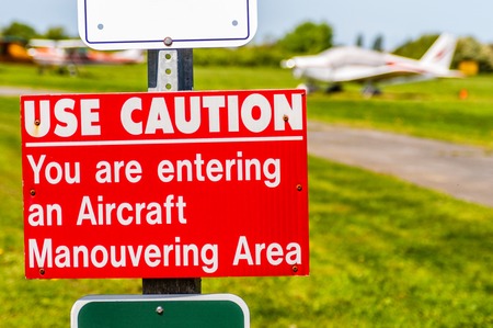 Aircraft manouvering red and white warning sign hung on post at airstrip.の写真素材