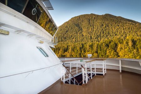Forward outside upper deck below cruise ship bridge passing by Alaska Inside Passage natural...
