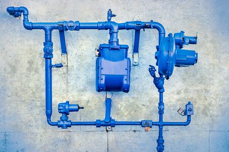 Side view of blue North American natural gas pipes and utility meter on old wallの写真素材