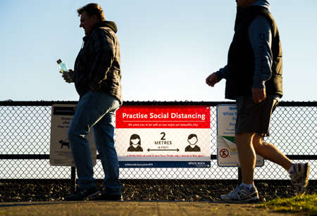 White Rock, Canada - March 25, 2020: Group of pedestrians walking past Covid-19 social distancing notificationのeditorial素材