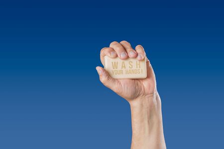 Caucasian male hand holding bar of soap with message Wash Your Hands