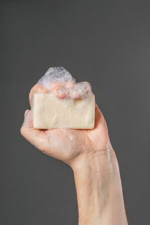 Caucasian male hand holding plain bar of soap with lather and bubblesの写真素材