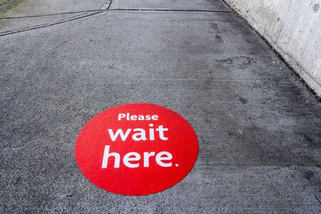 Red physical distancing sign on sidewalk during Coronavirus Covid-19 pandemicの写真素材